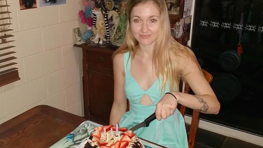 A young woman cutting a birthday cake