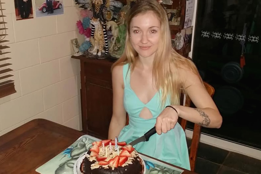 A young woman cutting a birthday cake