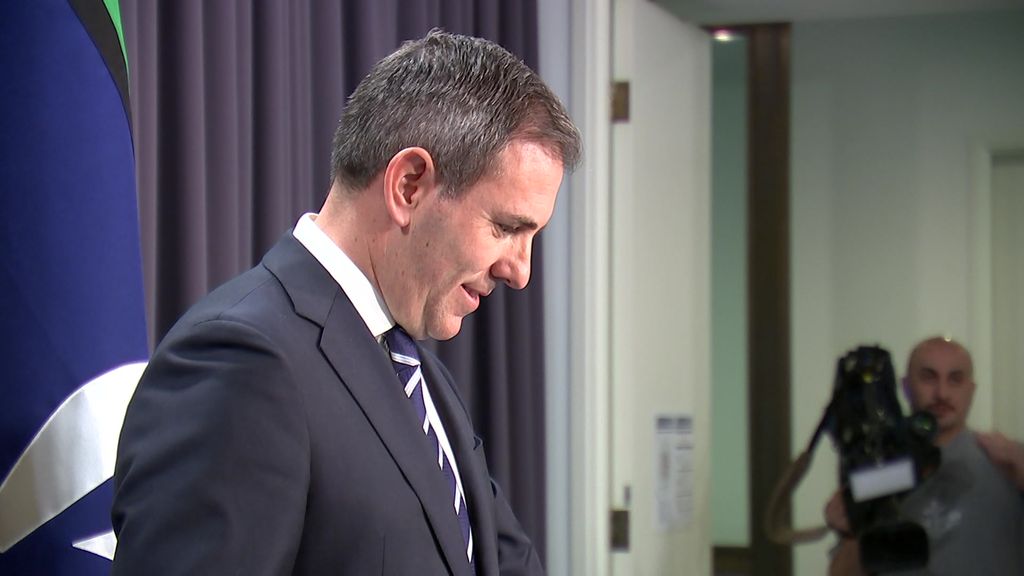 Jim Chalmers in profile with his head bowed ata  media conference.