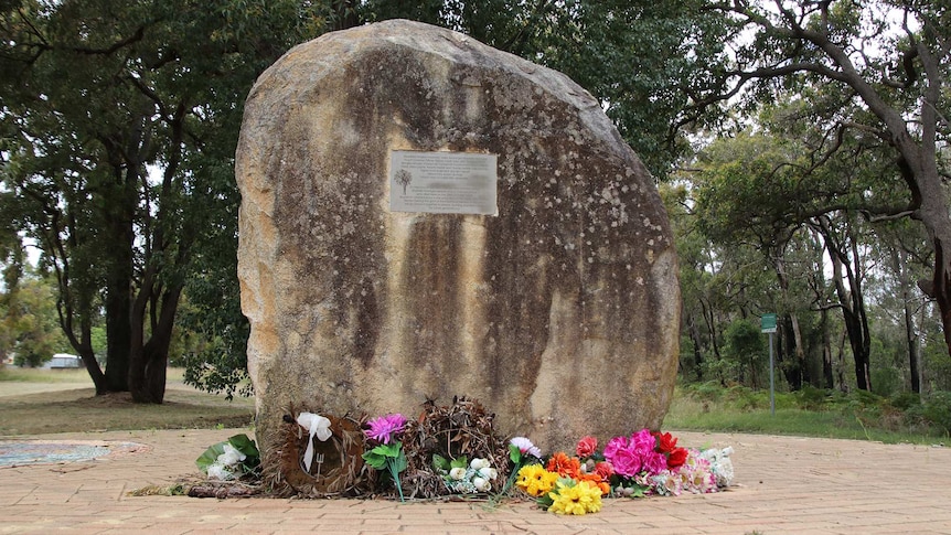 A large rock with a plaque on it in a park.