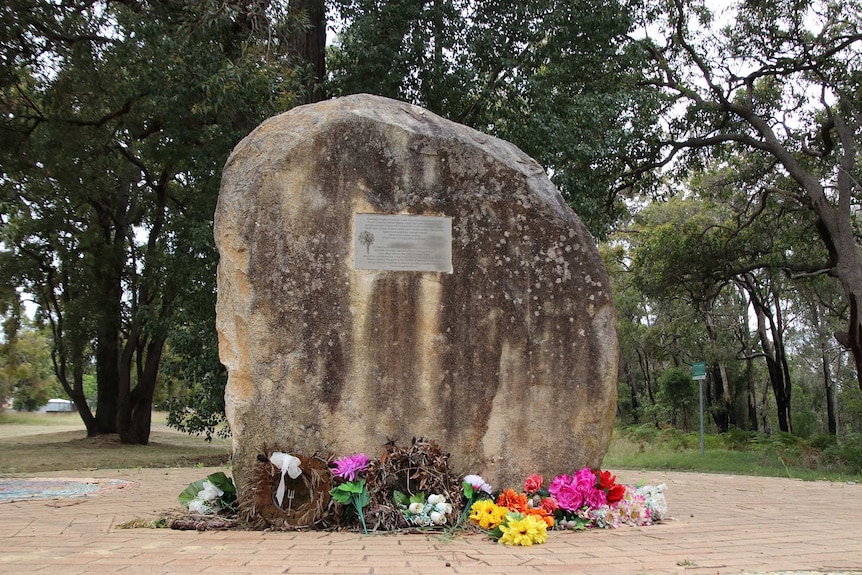 A large rock with a plaque on it in a park.