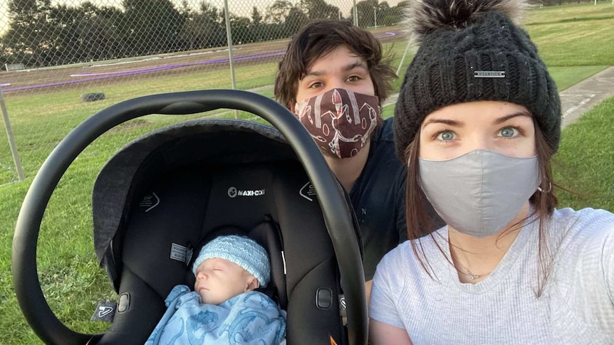 A baby in a pram with two parents wearing masks