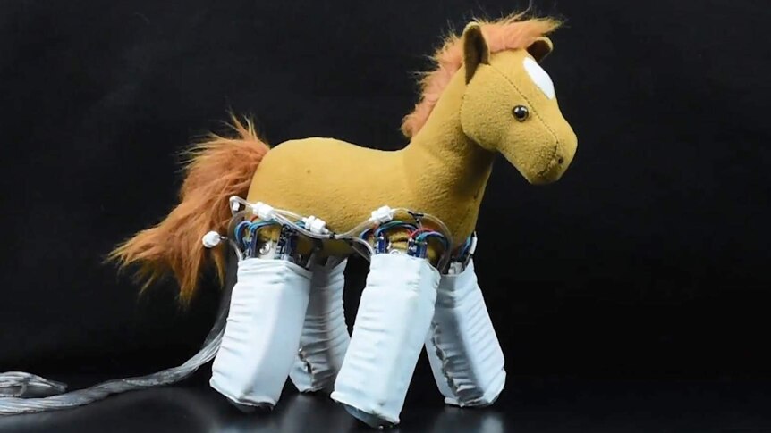 A stuffed toy horse with robot skins wrapped around its legs.