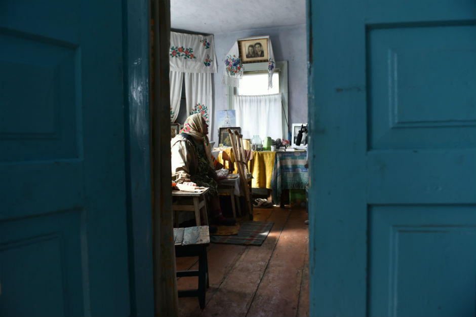 Maria Urupa is seen sitting on her bed through an open door.