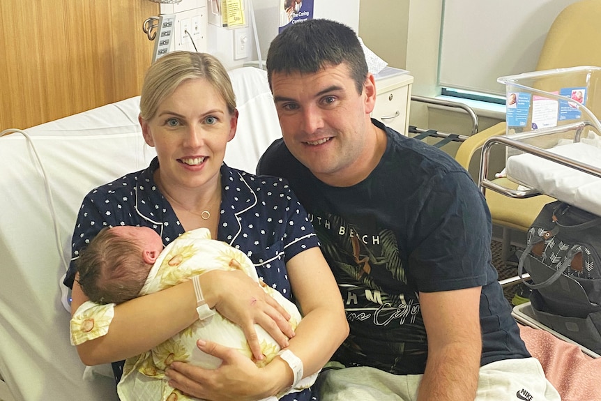 Aishling and Stephen Mohan, with their newborn son, sitting on a bed in a room at the Mater Hospital in Brisbane.
