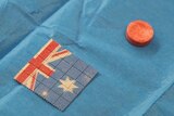 A small pill sitting next to a small tab of paper with an Australian flag pattern on it.