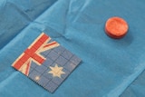 A small pill sitting next to a small tab of paper with an Australian flag pattern on it.