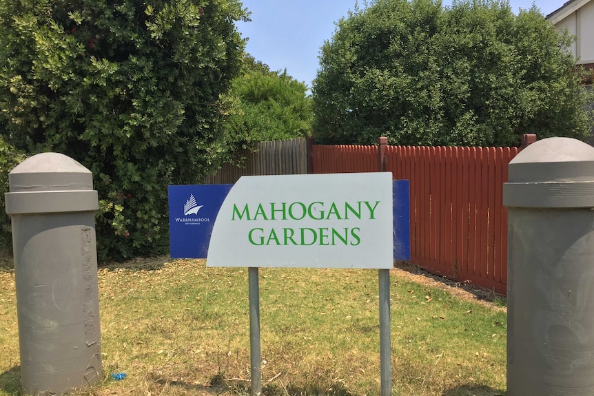 A sign in suburban park reads 'Mahogany Gardens'.