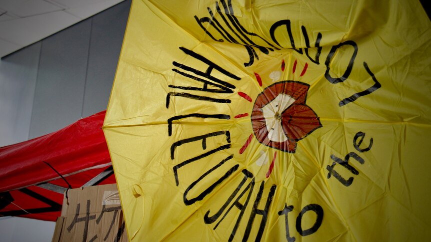 A crumbled yellow umbrella with "Sing Hallelujah to the Lord" written on it