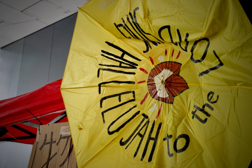 A crumbled yellow umbrella with "Sing Hallelujah to the Lord" written on it