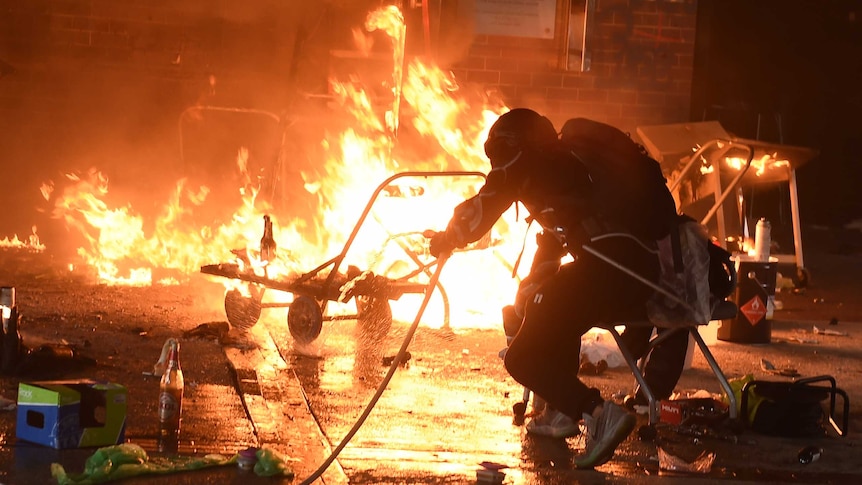 Student try to extinguish a fire at the entrance of Hong Kong Polytechnic University.