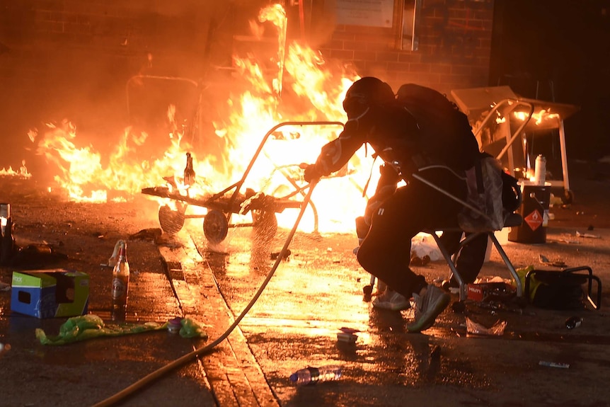 Student try to extinguish a fire at the entrance of Hong Kong Polytechnic University.