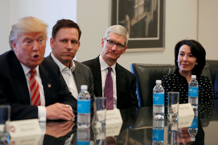 Donald Trump speaks as Peter Thiel, Tim Cook and Safra Catz look on .