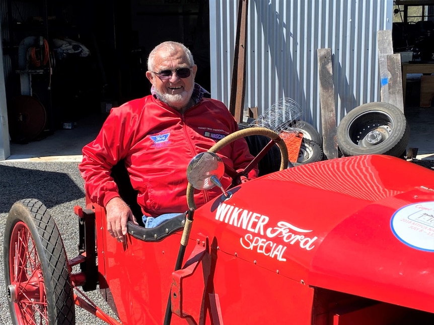 Man sitting in old red racing car the Wickner Ford Special