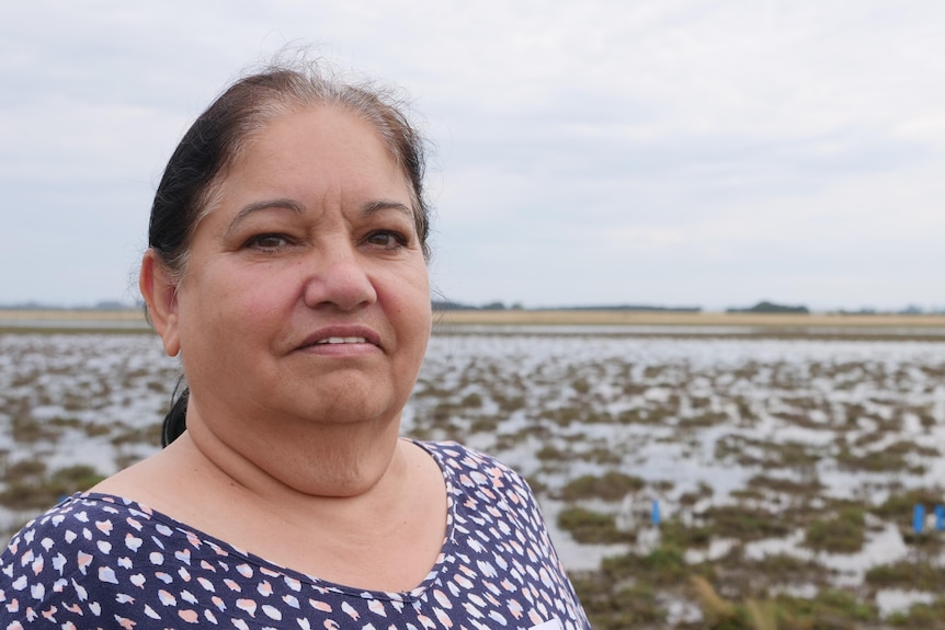 A Gunaikurnai woman standing in front of a coastal wetland