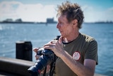 a man holding a camera by a port looking out of frame