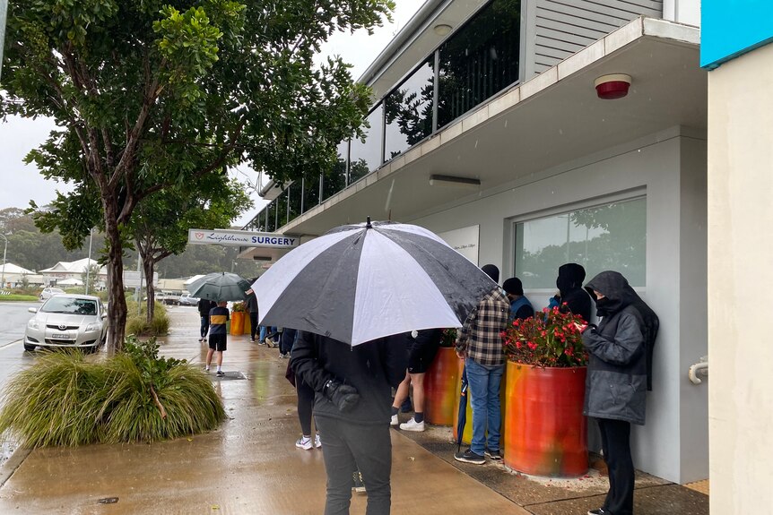 People with umbrellas outside a surgery 