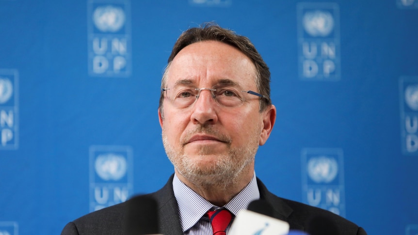 The United Nation's Achim Steiner stands in front of a blue UNDP screen. 
