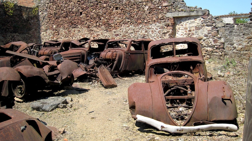 Car wrecks sit in the derelict village of Oradour-sur-Glane, France.