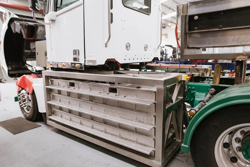 Close detail of large battery pack installed on side of truck between front and back wheels under the cab footwell.