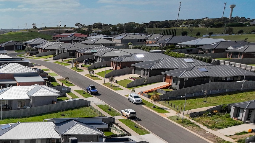 A line of new houses with identically coloured black roofs.