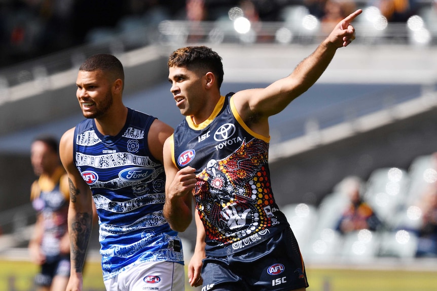Tyson Stengle points his hand up in the air wearing an Indigenous round jersey