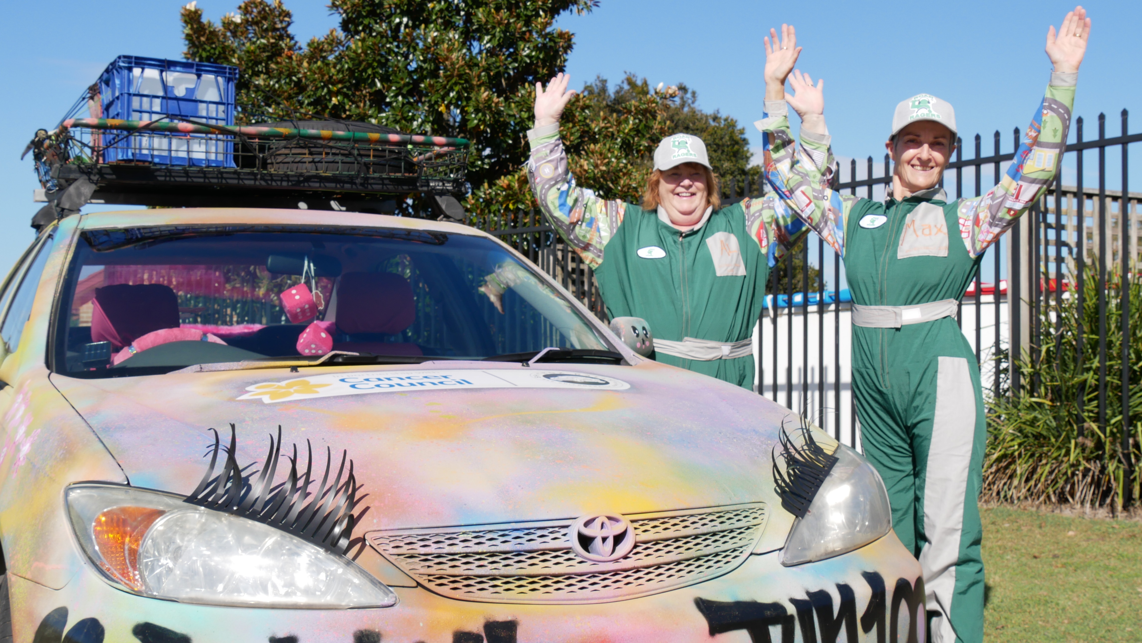 Allison and Maxine stand in front of their graffiti painted Toyota Camry with fake eyelashes. 