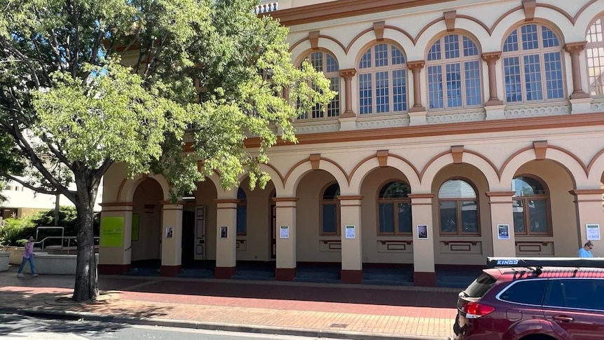 A building on a main street with a tree located to the left of it 