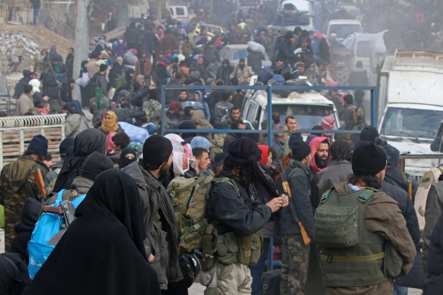 Rebel fighters and civilians gather as they wait to be evacuated.