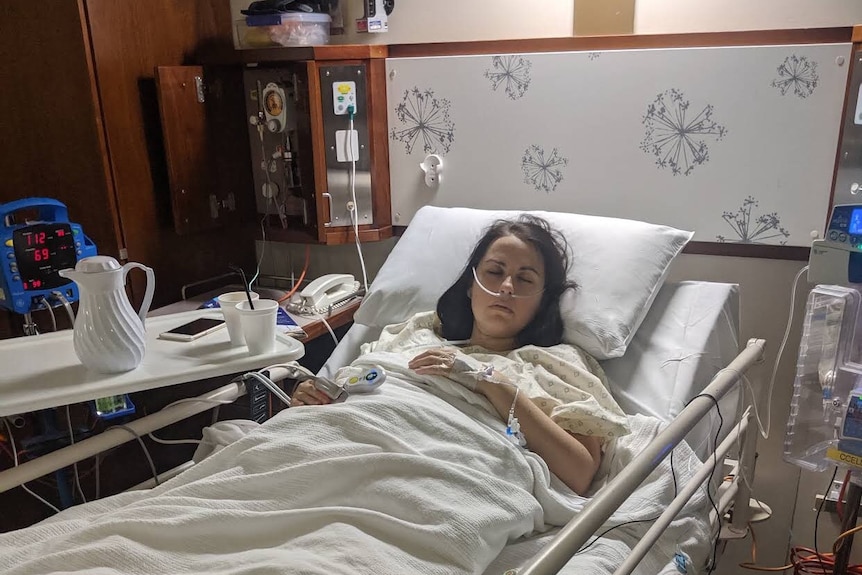 Caucasian woman with brown hair laying asleep in a hospital bed.