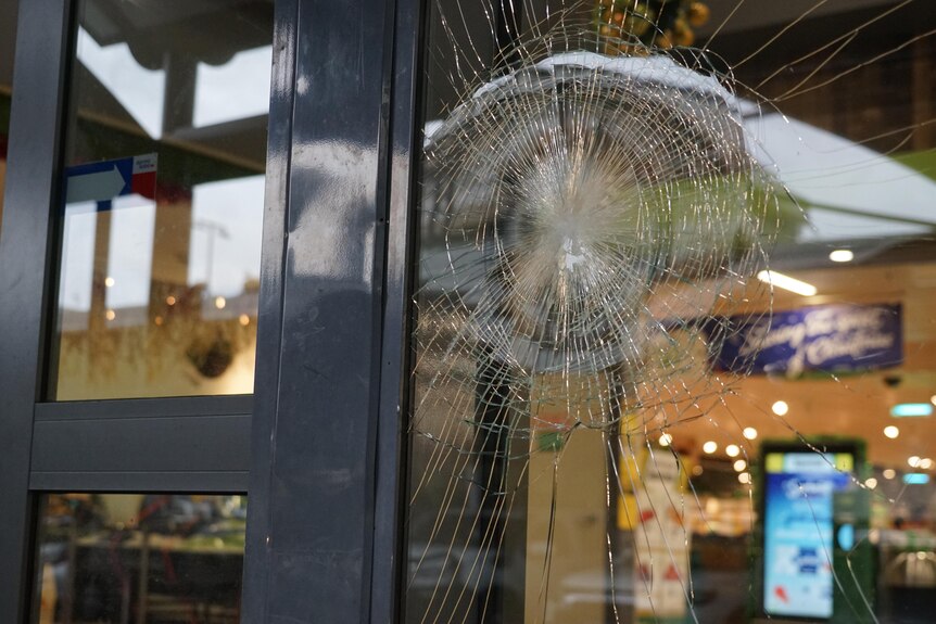 A glass door of a supermarket is smashed