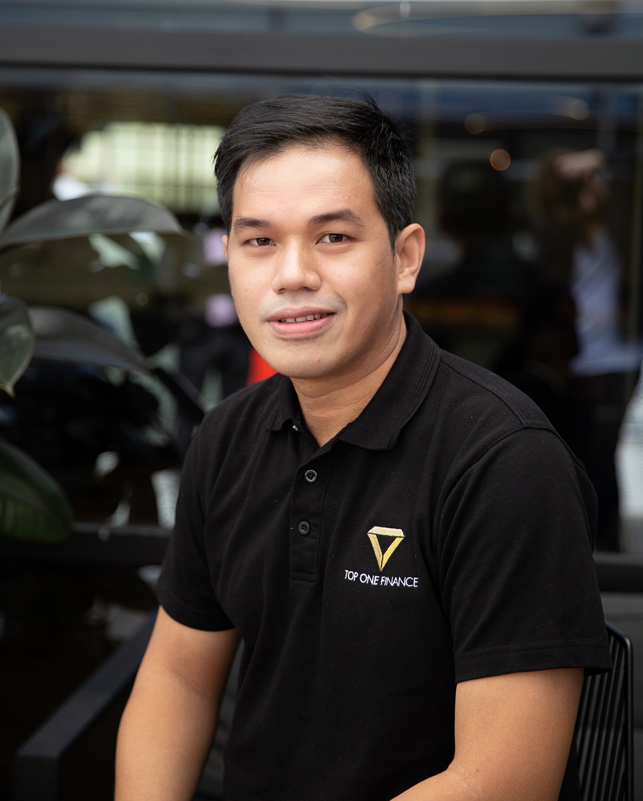 A man weaing a black polo and smiling to the camera.