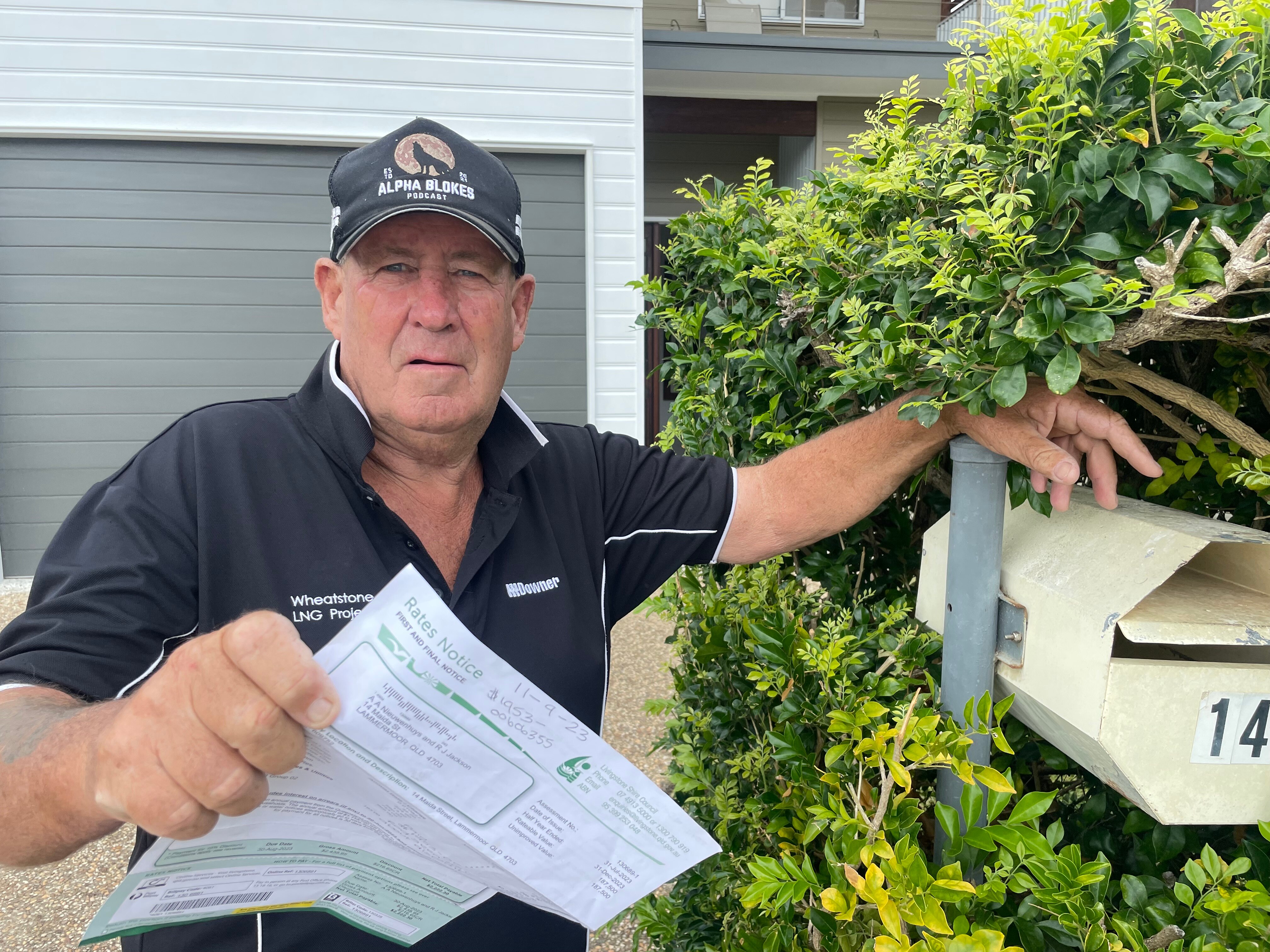 Man with a cap waves a rate notice.