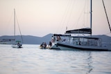 Queensland Yacht Charters boat in the water and smaller dingies with people on board.