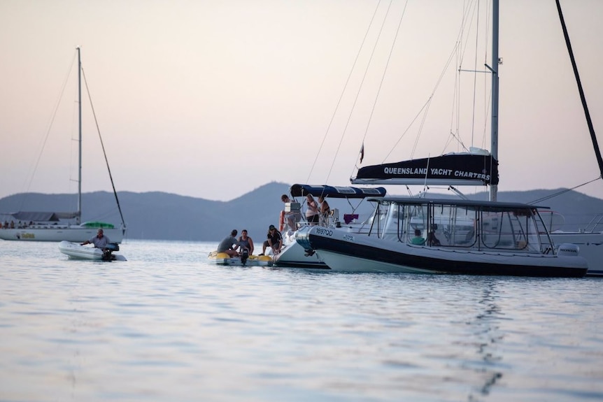 Queensland Yacht Charters boat in the water and smaller dingies with people on board.