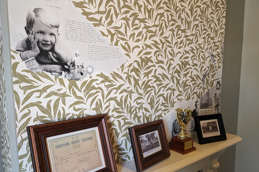 Wallpaper with a photo of a little boy incorporated into it, above a mantelpiece in an old home