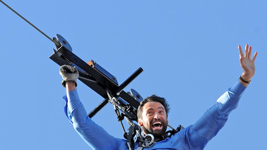 Hugh Jackman makes his aerial entrance on a flying-fox from the roof of the Opera House