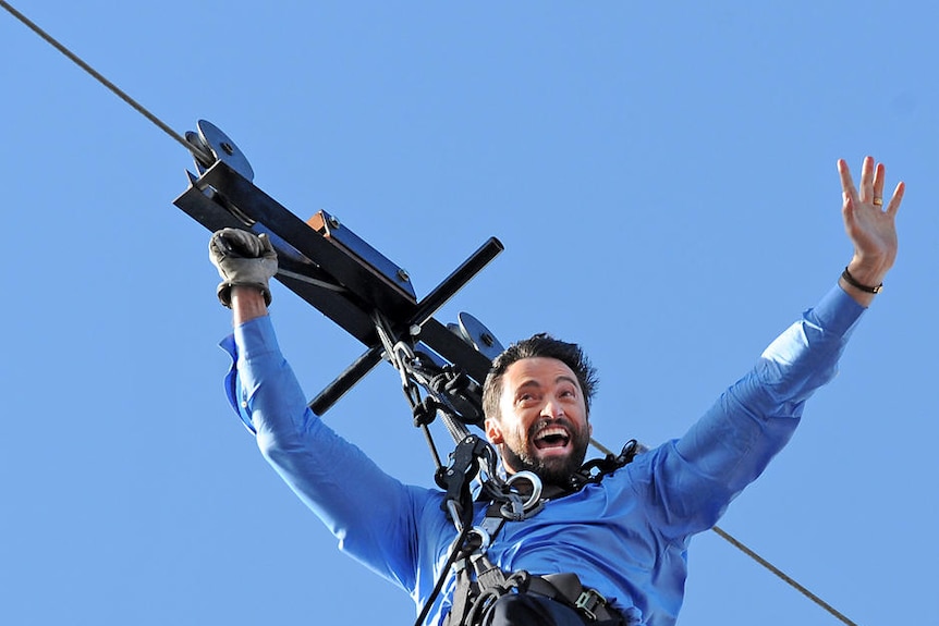 Hugh Jackman makes his aerial entrance on a flying-fox from the roof of the Opera House