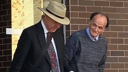 An elderly man exits court, a man and woman (his legal team) walk beside him.