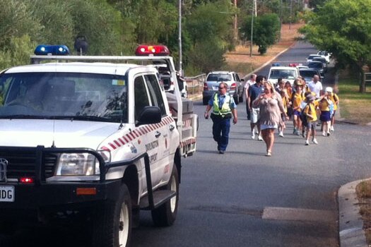 A shire truck leads a police officer and school kids to safe point