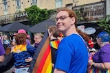 A woman holding a pride flag at a rally.