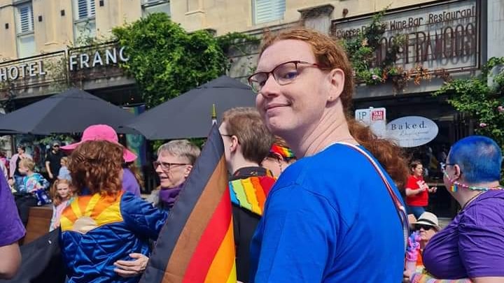 A woman holding a pride flag at a rally.