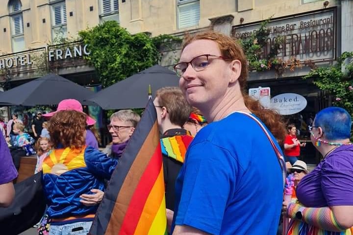 A woman holding a pride flag at a rally.