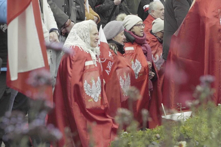 Elderly women pray on their knees.