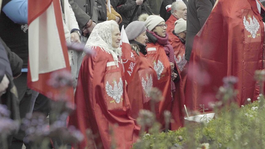 Elderly women pray on their knees.