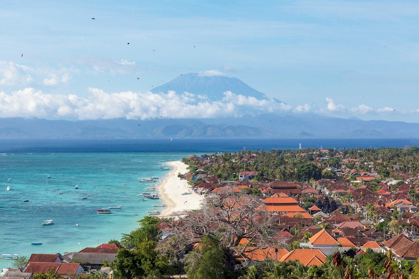 A tropical beach with a volcano looming in the background