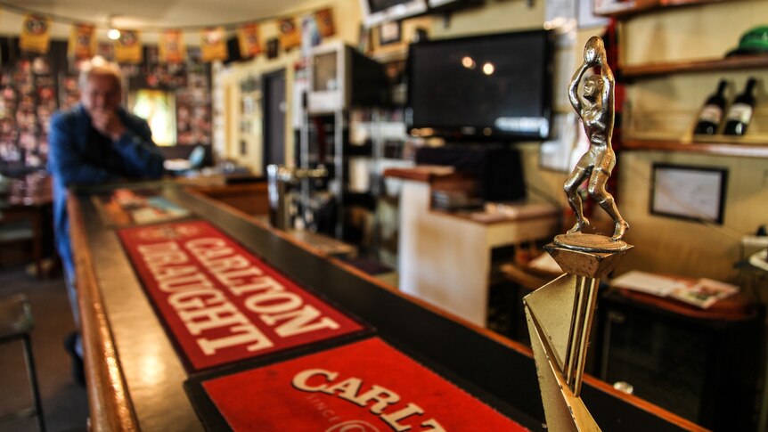 A football trophy sits on the bar, televisions and wine bottles on the wall behind.