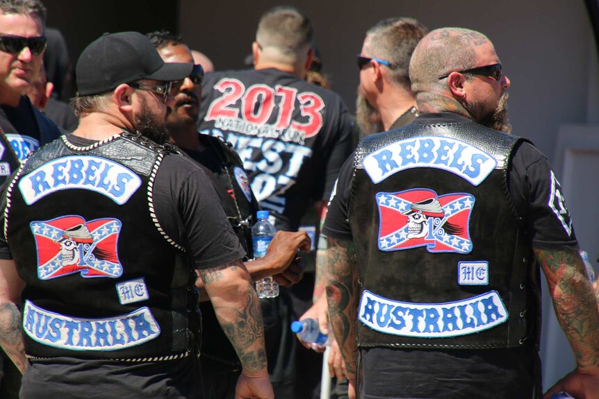 Two heavyset men wear 'Rebels' patches with a pic of a skull and "1%" on them.