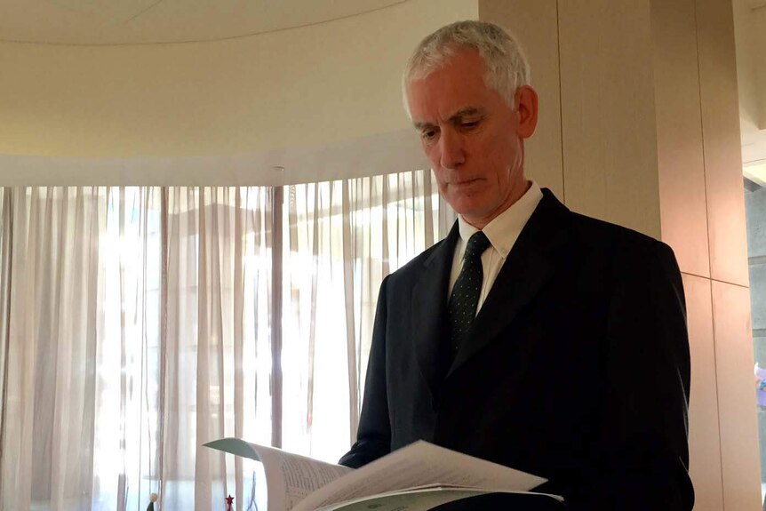 WA Inspector of Custodial Services Neil Morgan standing in an office reading his report.