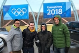 ABC team rugged up in coats standing in front of PyeongChang2018 and Olympic rings signs.